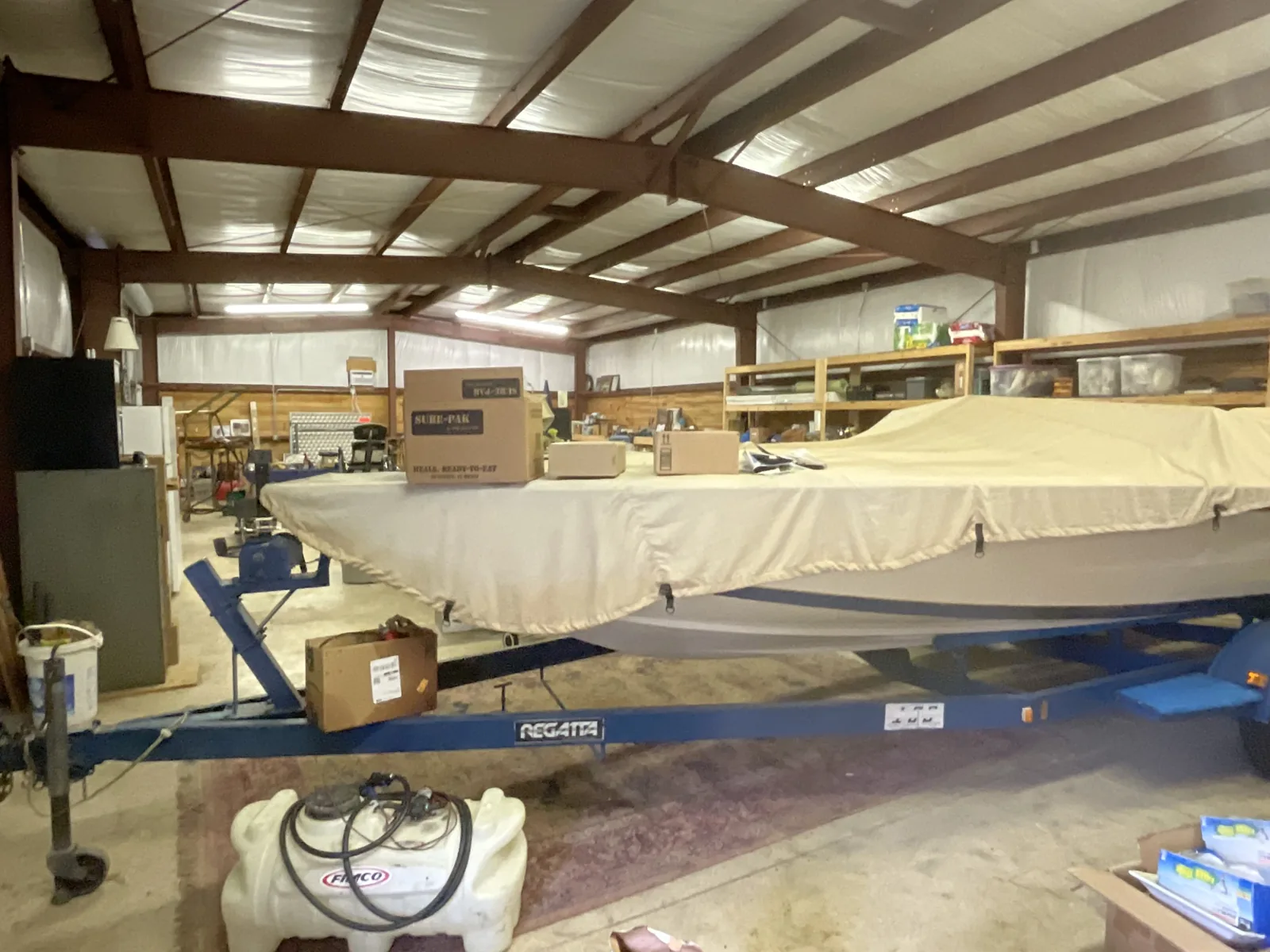 Interior of a climate-controlled building holding a boat and vehicles